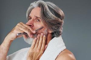 cuidando la barba. un anciano moderno y elegante con cabello gris está adentro foto