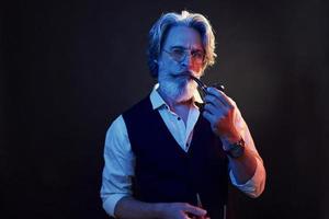 Conception of smoking. Stylish modern senior man with gray hair and beard is indoors photo