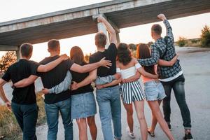 View from behind. Group of young cheerful friends having fun together. Party outdoors photo