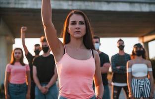 Woman on the front of crowd. Group of protesting young people that standing together. Activist for human rights or against government photo