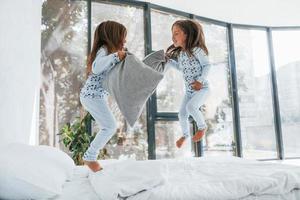 pelea de almohadas. dos niñas lindas en el interior de la casa juntas. niños divirtiéndose foto