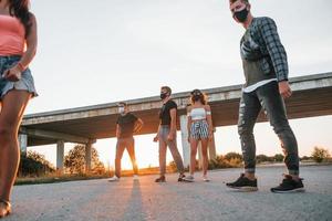 caminando por la carretera. grupo de jóvenes amigos alegres divirtiéndose juntos. fiesta al aire libre foto