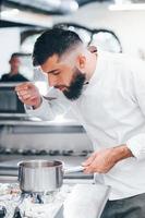 Chef in white uniform cooking food at kitchen. Busy day at work photo