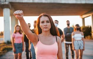 Woman on the front of crowd. Group of protesting young people that standing together. Activist for human rights or against government photo