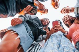 view from below. With phone. Group of young cheerful friends having fun together. Party outdoors photo