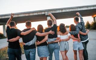 View from behind. Group of young cheerful friends having fun together. Party outdoors photo