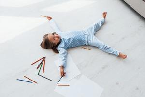 With pencils and paper. Creative cute little girl indoors at home alone. Child enjoying weekend photo