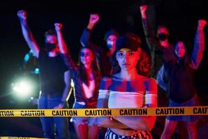 Calm woman standing in front of crowd. Group of protesting young people that standing together. Activist for human rights or against government photo