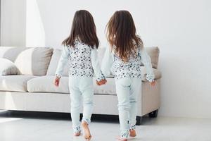 Holding each other's hand. Two cute little girls indoors at home together. Children having fun photo