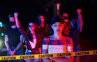 Calm woman standing in front of crowd. Group of protesting young people that standing together. Activist for human rights or against government photo