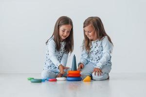 Playing with toy. Two cute little girls indoors at home together. Children having fun photo