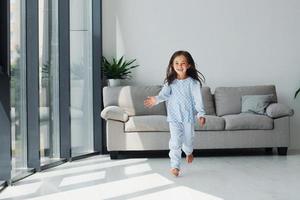 Running and having fun. Cute little girl indoors at home alone. Child enjoying weekend photo