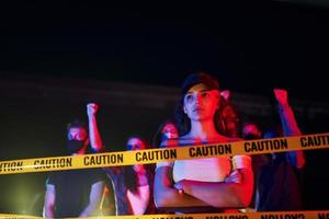 Calm woman standing in front of crowd. Group of protesting young people that standing together. Activist for human rights or against government photo