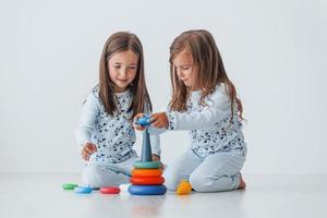 Playing with toy. Two cute little girls indoors at home together. Children having fun photo