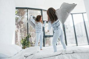 With pillows in hands. Two cute little girls indoors at home together. Children having fun photo