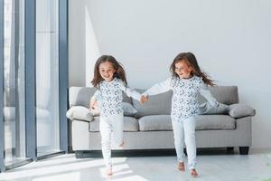 tomados de la mano. dos niñas lindas en el interior de la casa juntas. niños divirtiéndose foto