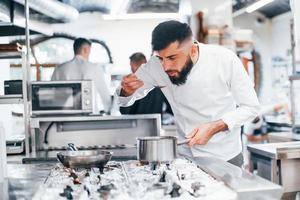 Chef in white uniform cooking food at kitchen. Busy day at work photo