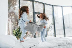 Pillow fight. Two cute little girls indoors at home together. Children having fun photo