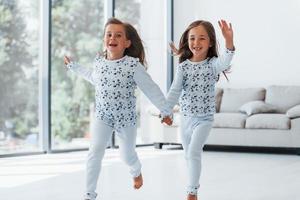 tomados de la mano. dos niñas lindas en el interior de la casa juntas. niños divirtiéndose foto