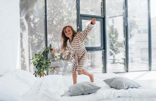 saltando en el sofá. linda niña adentro en casa sola. niño disfrutando el fin de semana foto