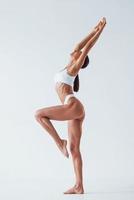 Doing exercises. Beautiful woman with slim body in underwear is in the studio photo