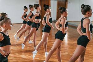 Group of female kids practicing athletic exercises together indoors photo