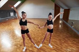 Training routine. Group of female kids practicing athletic exercises together indoors photo