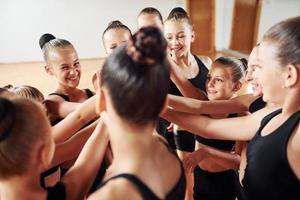 Many of people. Group of female kids practicing athletic exercises together indoors photo