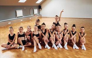 posando para una cámara. grupo de niñas practicando ejercicios atléticos juntas en el interior foto