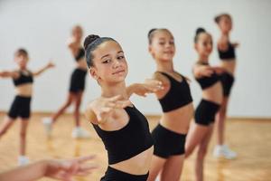 de pie y haciendo movimientos sincronizados. grupo de niñas practicando ejercicios atléticos juntas en el interior foto