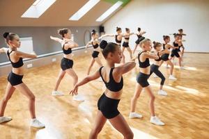 Side view of group of female kids that practicing athletic exercises together indoors photo