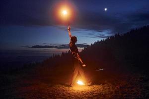 Fire show by man in night Carphatian mountains. Beautiful landscape photo