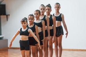 Daily routine. Group of female kids practicing athletic exercises together indoors photo