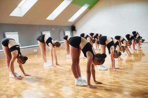 vista lateral de un grupo de niñas que practican ejercicios atléticos juntas en el interior foto