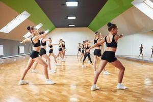 Side view of group of female kids that practicing athletic exercises together indoors photo