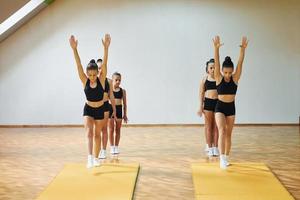 Daily routine. Group of female kids practicing athletic exercises together indoors photo