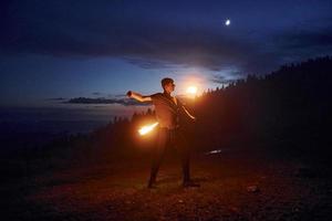 Fire show by man in night Carphatian mountains. Beautiful landscape photo