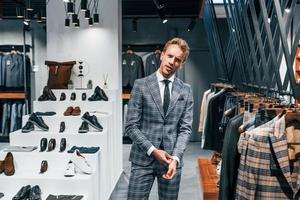 en chaqueta con corbata. chico joven en una tienda moderna con ropa nueva. ropa elegante y cara para hombres
