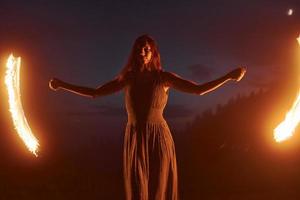 foto con una larga exposición. espectáculo de fuego de una mujer vestida en las montañas carphatian nocturnas. Precioso paisaje