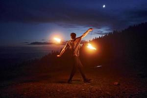 Fire show by man in night Carphatian mountains. Beautiful landscape photo