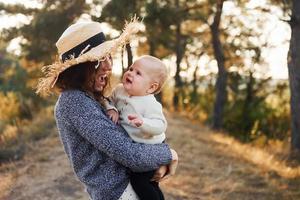 Playing together. Young mother with her little baby rests outdoors at autumn season photo