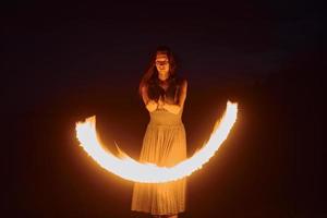 Fire show by woman in dress in night Carphatian mountains. Beautiful landscape photo