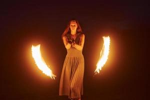 Fire show by woman in dress in night Carphatian mountains. Beautiful landscape photo