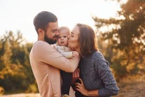 Happy family of mother, family and little baby rests outdoors. Beautiful sunny autumn nature photo