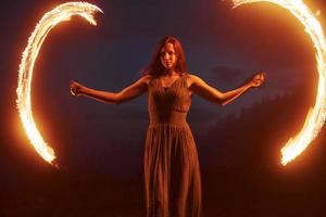 Photo with a long exposure. Fire show by woman in dress in night Carphatian mountains. Beautiful landscape