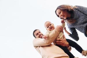 View from below. Happy family of mother, family and little baby rests outdoors. Beautiful sunny autumn nature photo