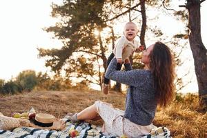 Young mother with her little baby rests outdoors at autumn season photo