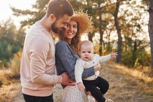 Happy family of mother, family and little baby rests outdoors. Beautiful sunny autumn nature photo