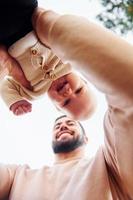 Bearded father playing with his child outdoors at sunny daytime outdoors photo