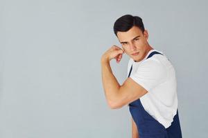 muestra bíceps. Listo para trabajar. trabajador de sexo masculino en uniforme azul de pie dentro del estudio contra el fondo blanco foto